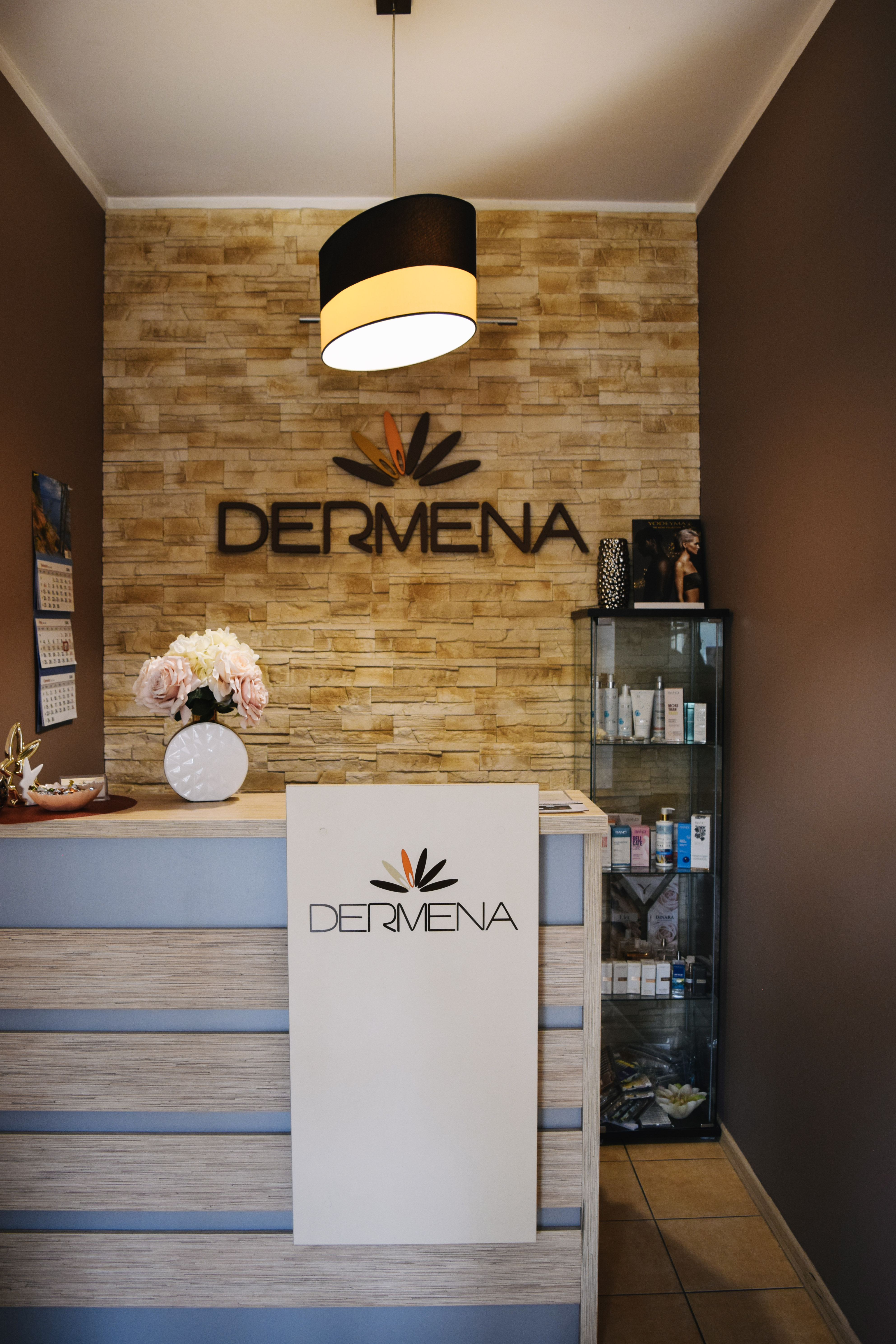 Recepcja Salonu Kosmetycznego Dermena w Toruniu - logo na ścianie z kamienia